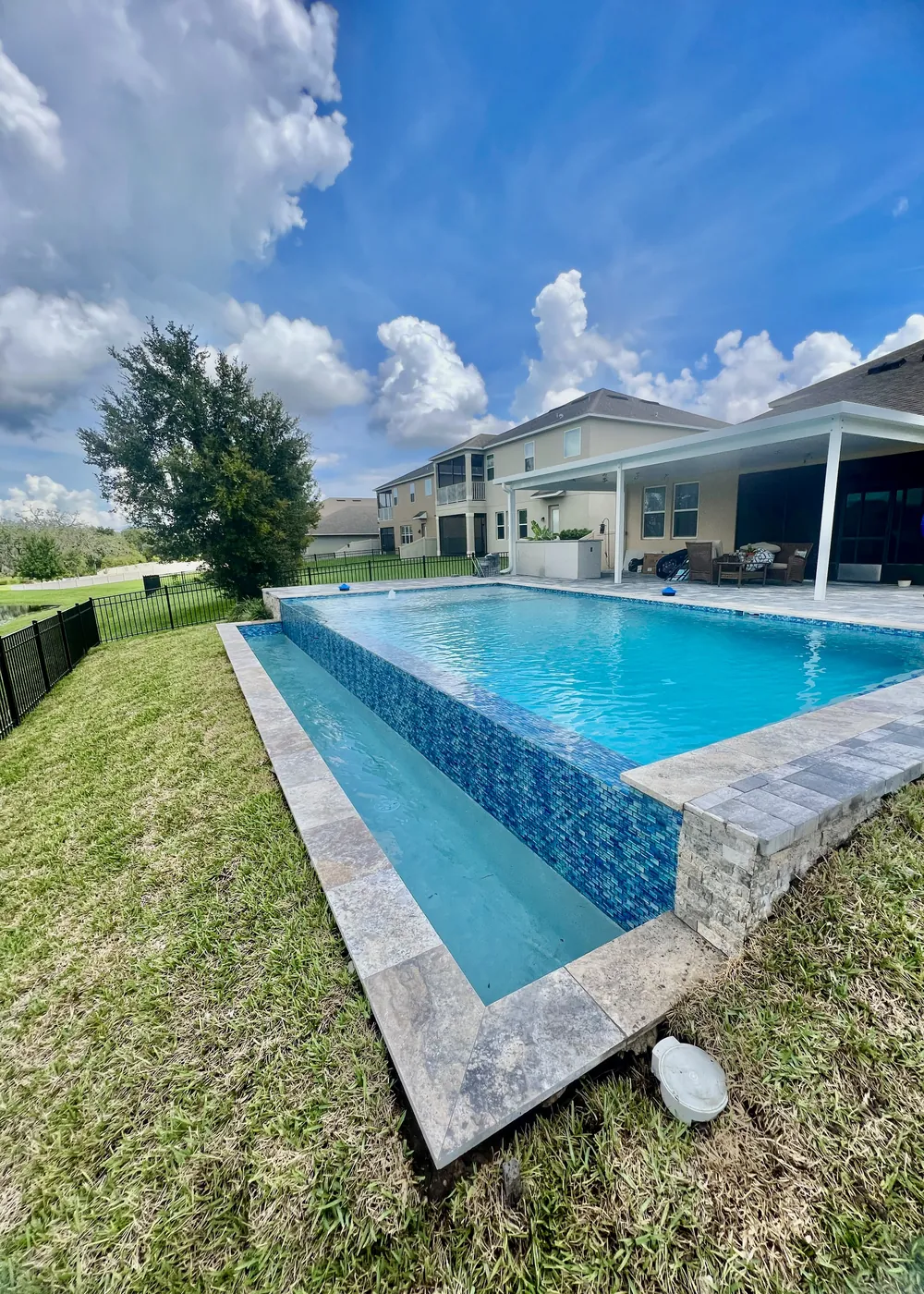 Travertine coping framing a blue tiled pool